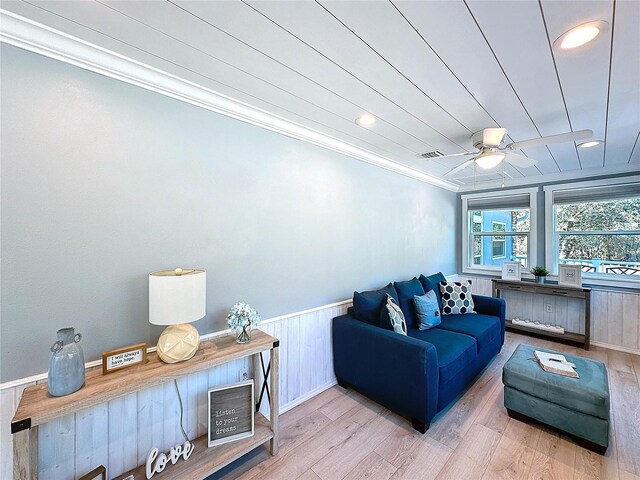 living room featuring light hardwood / wood-style flooring, ornamental molding, and ceiling fan