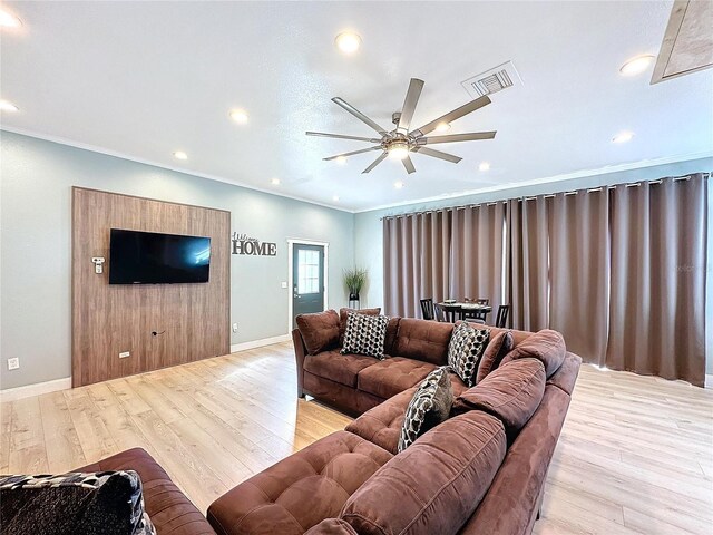 living room featuring ornamental molding, ceiling fan, and light wood-type flooring