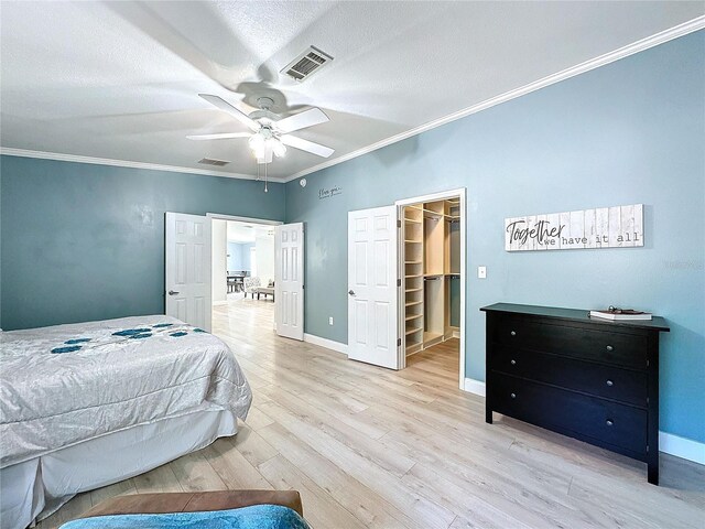 bedroom with light wood-style floors, visible vents, ornamental molding, and baseboards