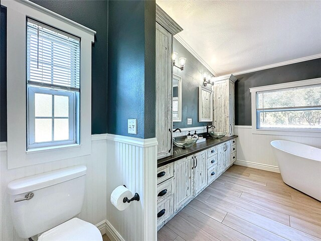 bathroom with toilet, ornamental molding, vanity, a tub, and hardwood / wood-style floors