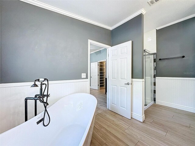 full bathroom featuring a wainscoted wall, crown molding, a freestanding bath, a stall shower, and wood finished floors