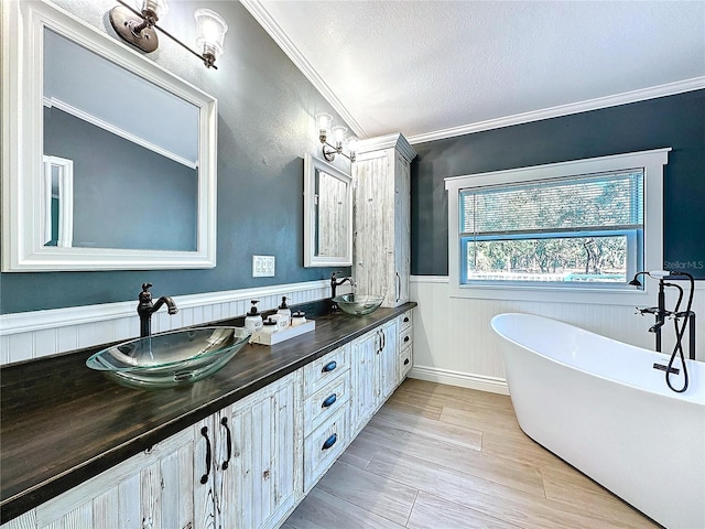 bathroom featuring a washtub, hardwood / wood-style floors, vanity, ornamental molding, and a textured ceiling