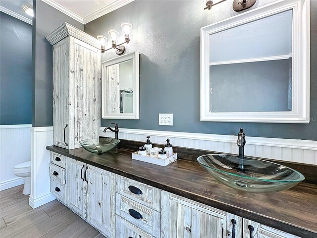 bathroom featuring hardwood / wood-style flooring, vanity, crown molding, and toilet