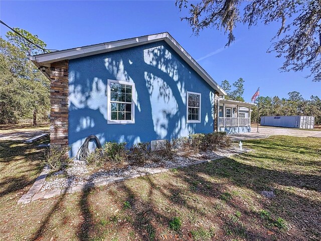 view of side of home featuring a lawn and stucco siding