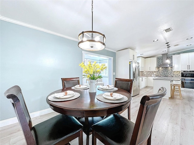 dining space with baseboards, light wood finished floors, visible vents, and crown molding