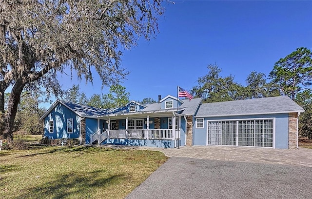 view of front of home with a garage, covered porch, decorative driveway, and a front yard