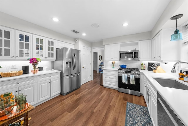 kitchen with sink, hanging light fixtures, backsplash, stainless steel appliances, and white cabinets