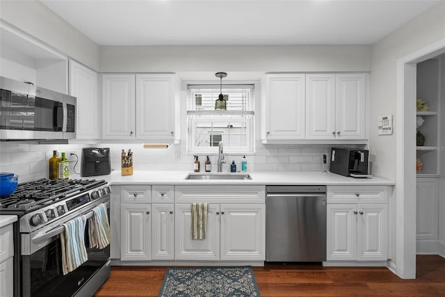 kitchen with pendant lighting, white cabinetry, sink, decorative backsplash, and stainless steel appliances