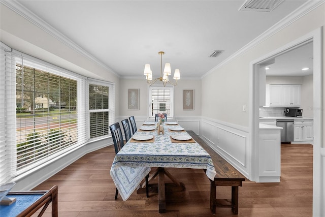 dining room featuring an inviting chandelier, hardwood / wood-style floors, ornamental molding, and a healthy amount of sunlight