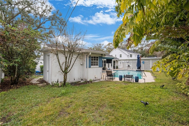 back of property with a patio, a fenced in pool, and a lawn