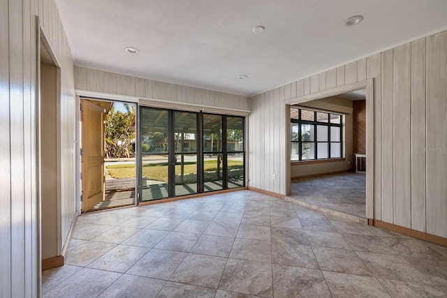 tiled spare room featuring wooden walls