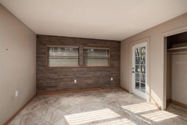 unfurnished bedroom featuring wooden walls, access to exterior, and a closet