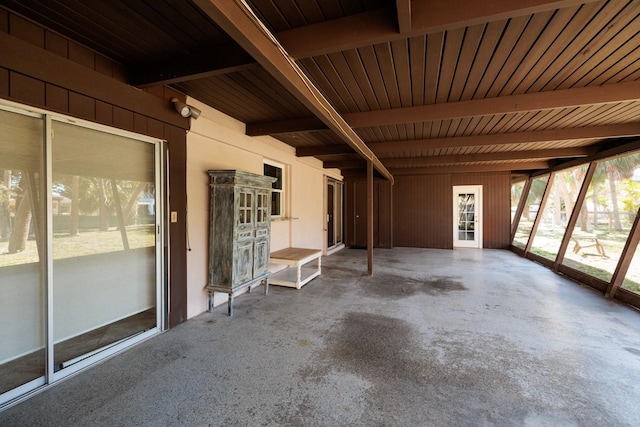 unfurnished sunroom featuring a wealth of natural light, wooden ceiling, and beam ceiling