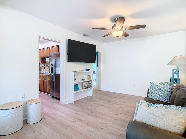 living room with sink, light hardwood / wood-style floors, and ceiling fan