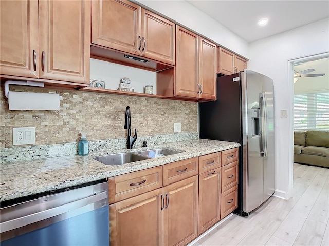 kitchen with sink, ceiling fan, light hardwood / wood-style floors, stainless steel appliances, and light stone countertops