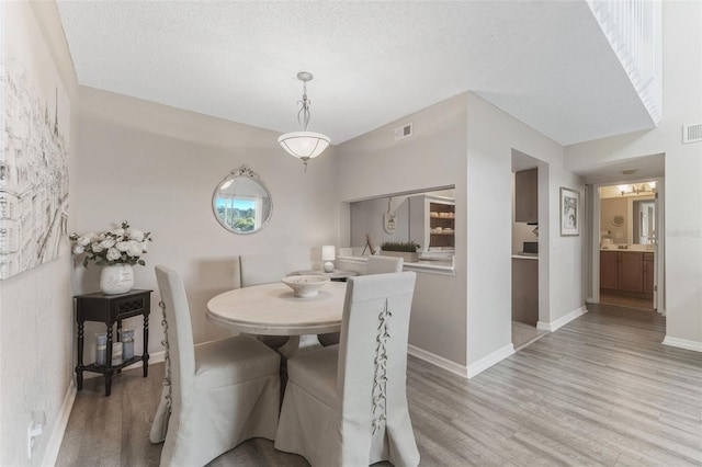 dining space with a textured ceiling and light wood-type flooring