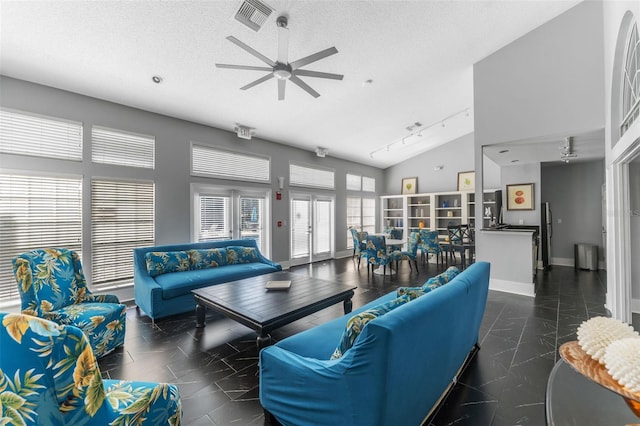 living room featuring rail lighting, lofted ceiling, ceiling fan, and a textured ceiling