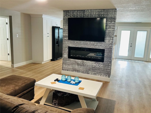 living room featuring a textured ceiling, light hardwood / wood-style floors, and french doors