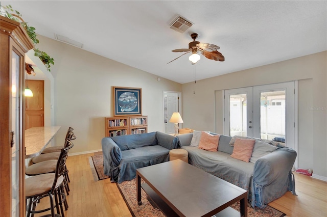 living room with french doors, ceiling fan, vaulted ceiling, and light hardwood / wood-style flooring