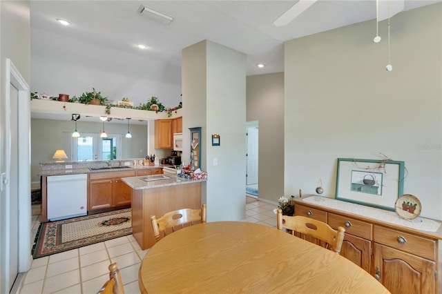 kitchen with light tile patterned flooring, white appliances, kitchen peninsula, and hanging light fixtures