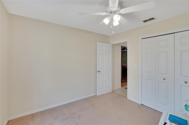 unfurnished bedroom with light colored carpet, a closet, and ceiling fan