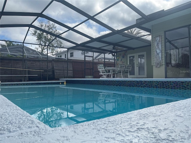 view of pool with a patio, glass enclosure, and french doors