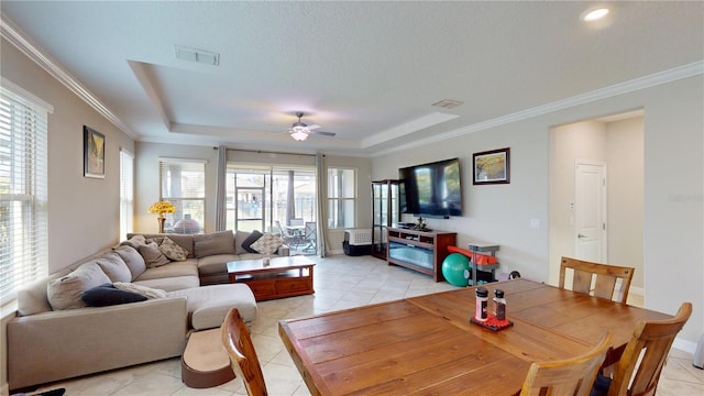 tiled living room with crown molding, ceiling fan, a tray ceiling, and a textured ceiling