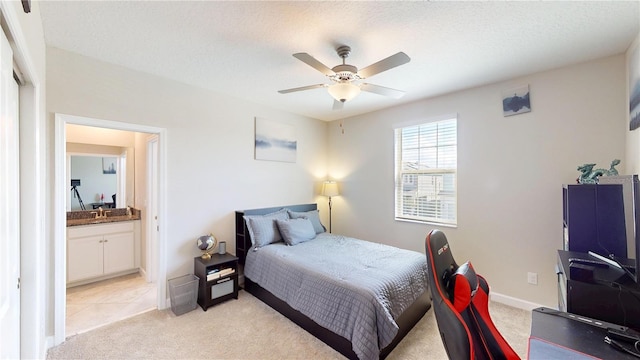 bedroom featuring ensuite bath, light colored carpet, and a textured ceiling