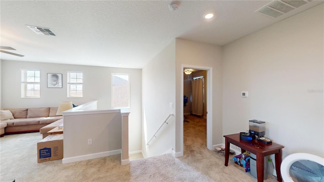 interior space featuring light colored carpet and a textured ceiling