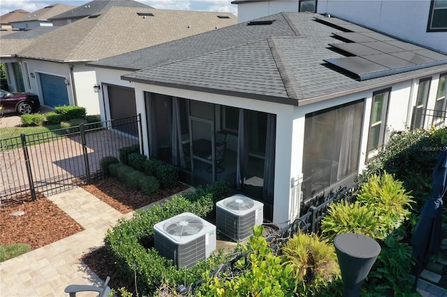 exterior space featuring central AC unit, a sunroom, and solar panels