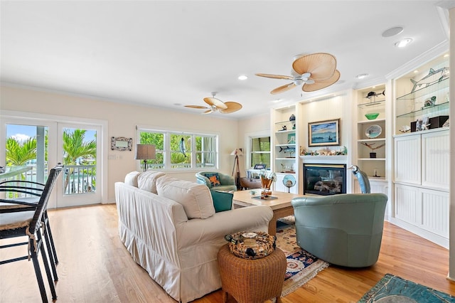 living room featuring crown molding, ceiling fan, and light wood-type flooring