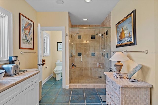 bathroom featuring tile patterned flooring, walk in shower, vanity, and toilet