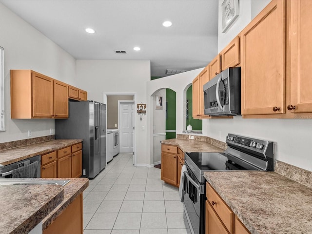 kitchen featuring stainless steel appliances, washer and dryer, and light tile patterned floors