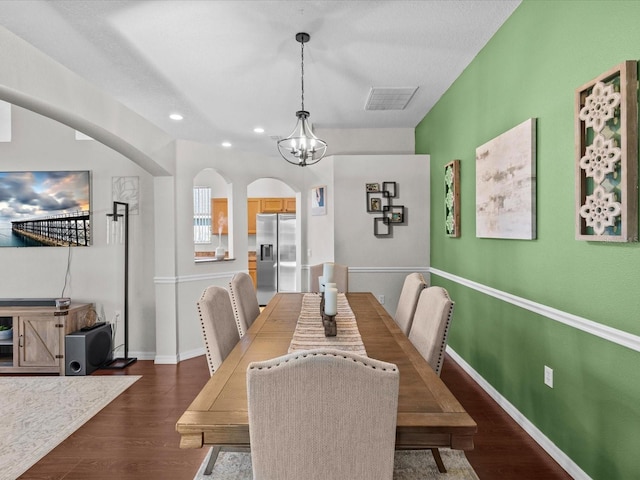 dining room featuring dark wood-type flooring, a chandelier, and a textured ceiling