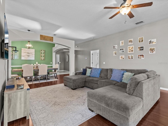 living room with ceiling fan, dark hardwood / wood-style floors, and a textured ceiling