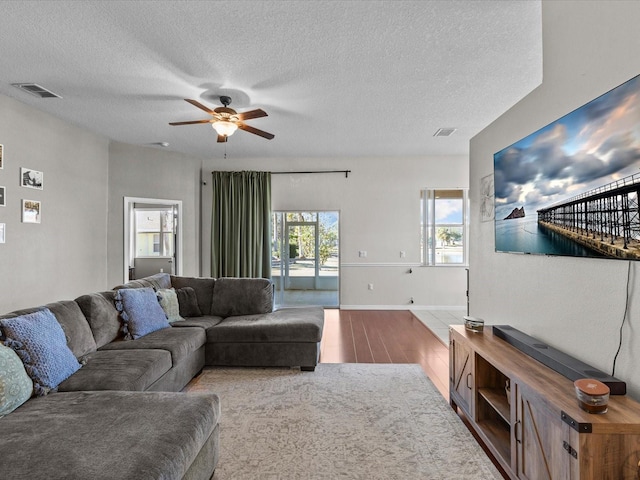 living room featuring ceiling fan and a textured ceiling