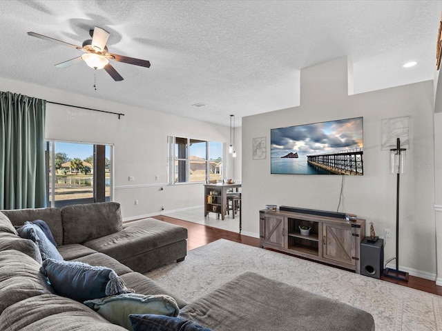 living room featuring hardwood / wood-style floors, plenty of natural light, a textured ceiling, and ceiling fan