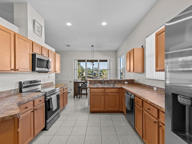 kitchen featuring appliances with stainless steel finishes, decorative light fixtures, sink, light tile patterned floors, and kitchen peninsula