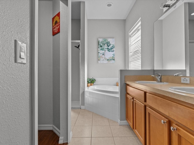 bathroom with tile patterned floors, tiled bath, and vanity