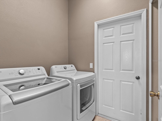 laundry area with independent washer and dryer and light tile patterned flooring