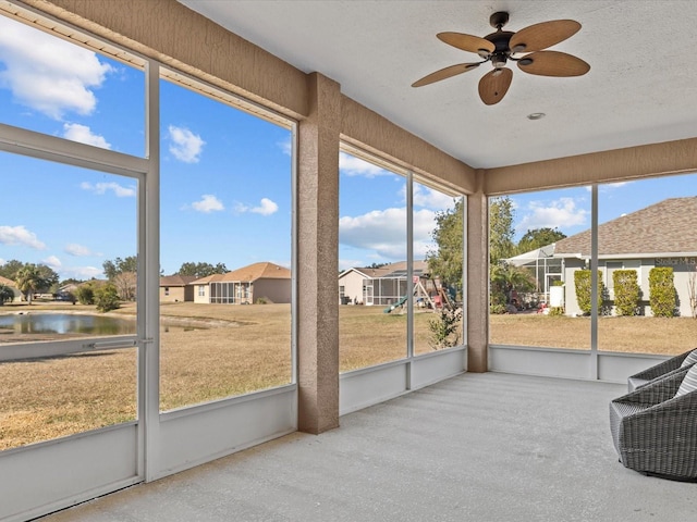 sunroom featuring a water view and ceiling fan