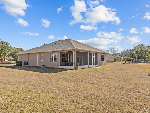 rear view of house with central AC unit, a lawn, and a sunroom