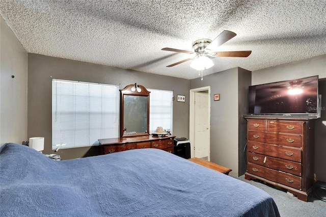 bedroom with ceiling fan, carpet floors, and a textured ceiling