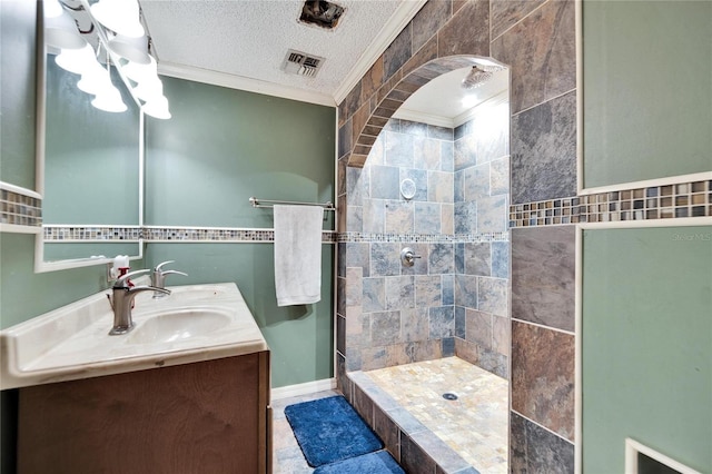 bathroom featuring vanity, crown molding, a textured ceiling, and tiled shower