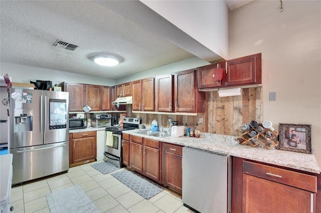 kitchen with stainless steel appliances, sink, light tile patterned floors, and a textured ceiling