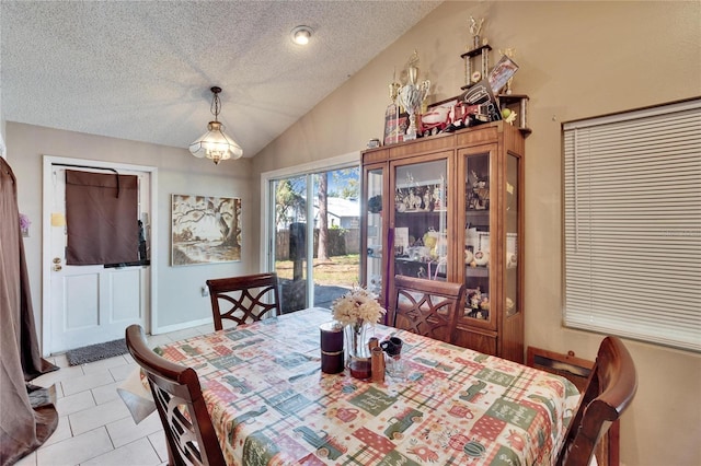 dining room featuring lofted ceiling, light tile patterned floors, and a textured ceiling