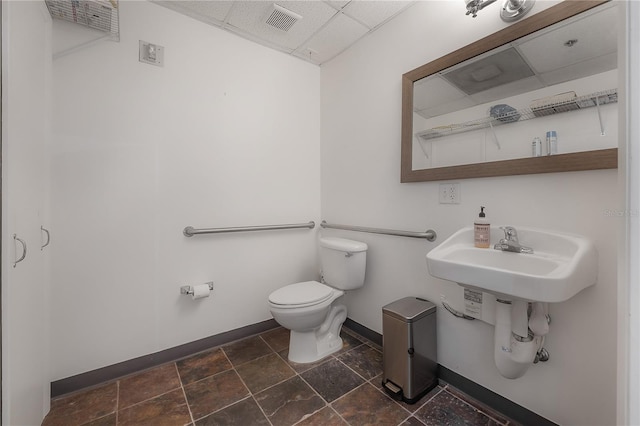 bathroom with a paneled ceiling and toilet