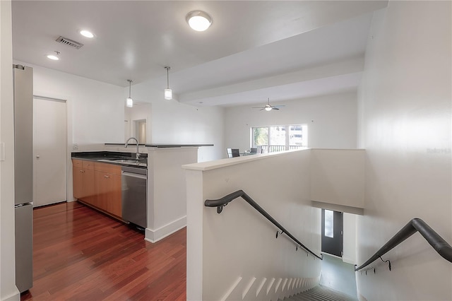 kitchen with hanging light fixtures, appliances with stainless steel finishes, dark wood-type flooring, and kitchen peninsula