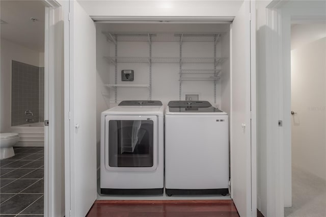 washroom featuring washer and clothes dryer and dark tile patterned flooring