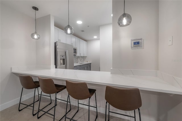 kitchen featuring a breakfast bar, white cabinetry, tasteful backsplash, kitchen peninsula, and stainless steel appliances